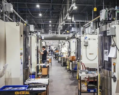Industrial CNC machines lined up across a large, organized factory floor.